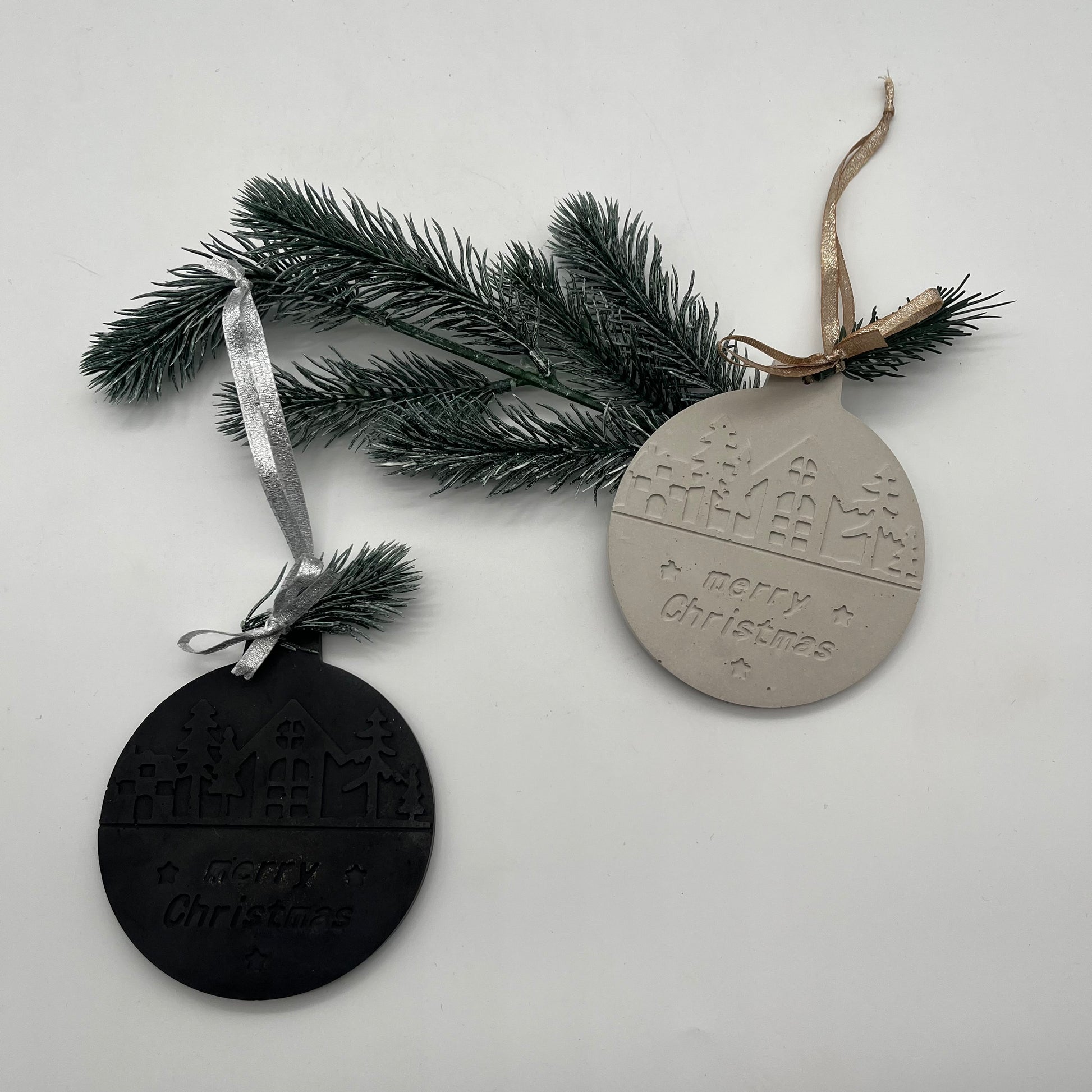 Beton-Anhänger „Christmas Magic“ Christbaumkugel in Grau und Schwarz mit Weihnachtsmotiv auf Tannenzweig.