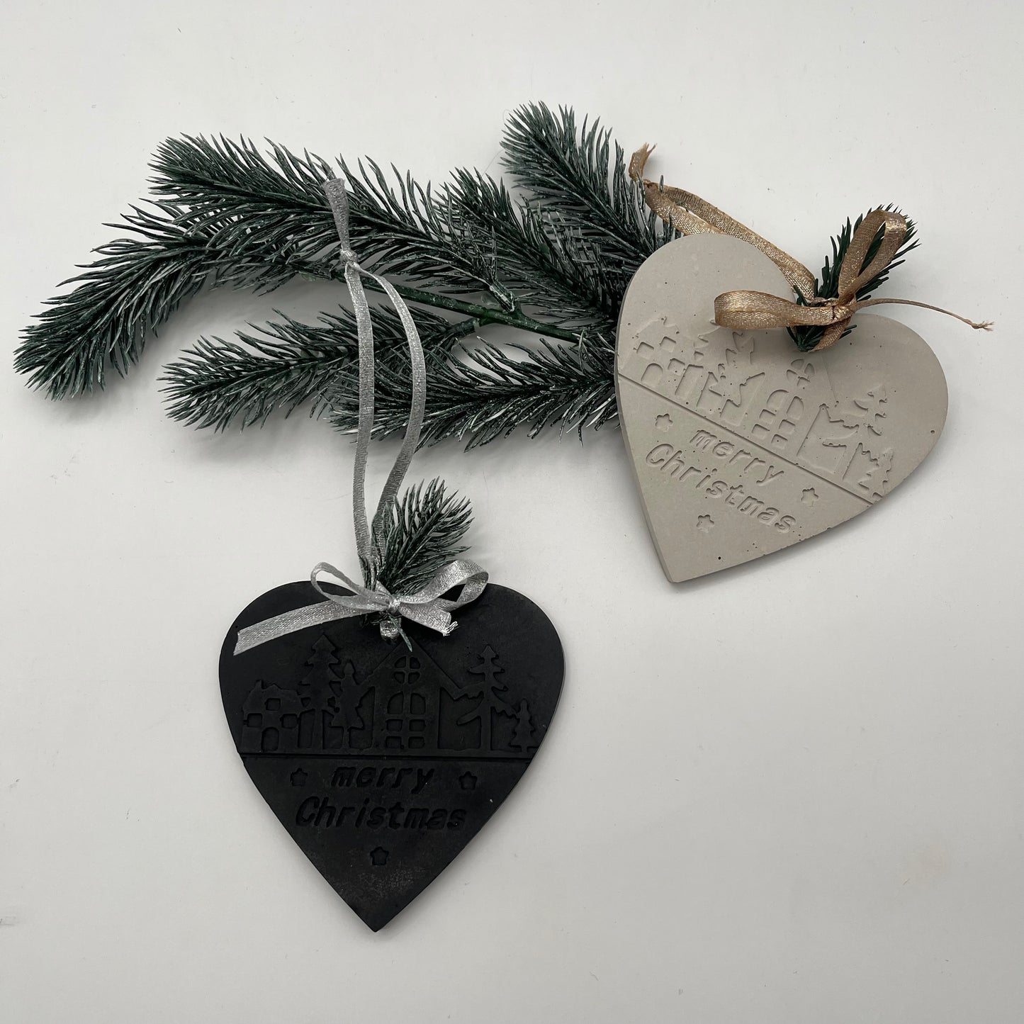 Handgefertigter Beton-Anhänger Herz „Christmas Magic“ in Grau und Schwarz auf Tannenzweig.