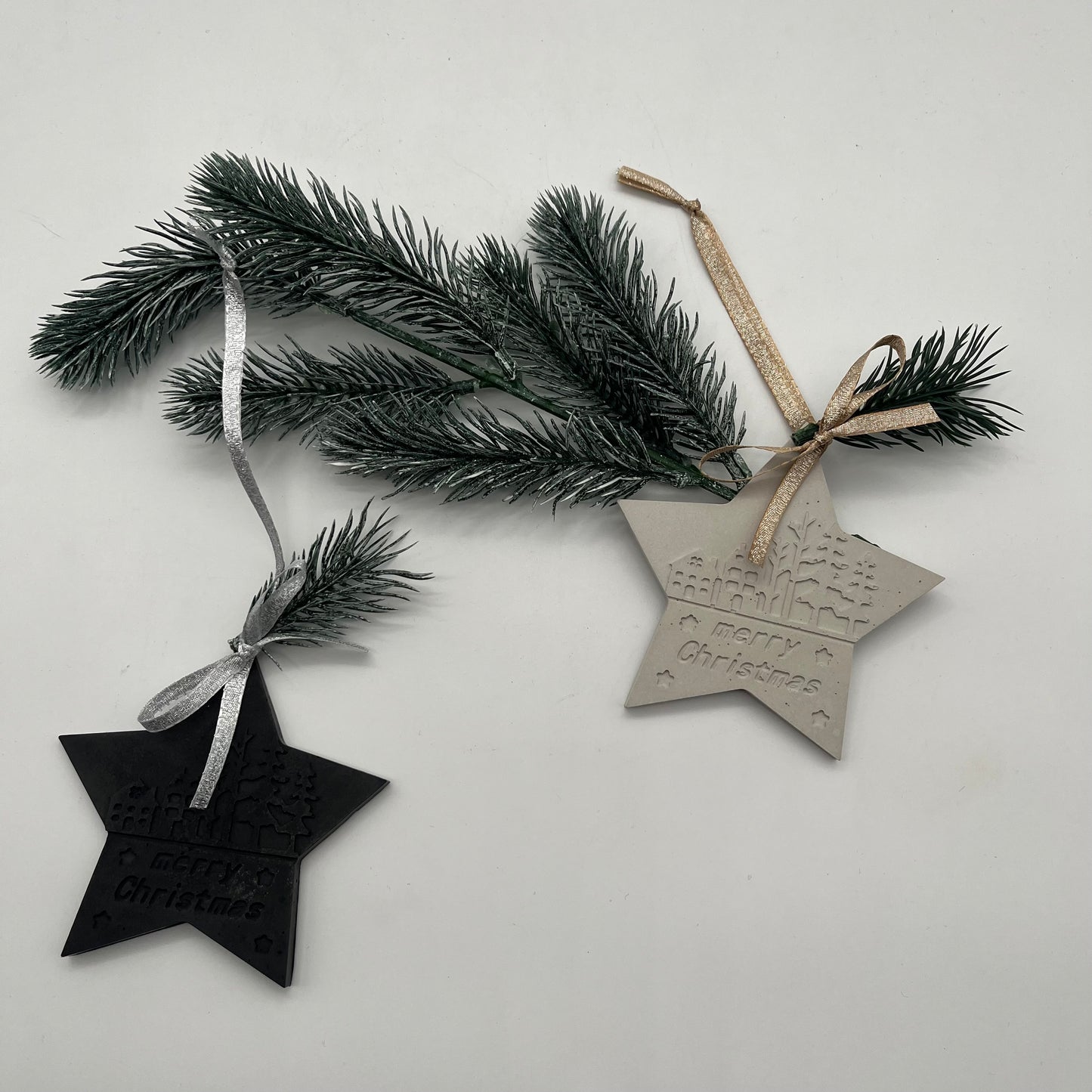Beton-Anhänger Stern „Christmas Magic“ in Grau und Schwarz auf Tannenzweig – moderne Weihnachtsdeko.