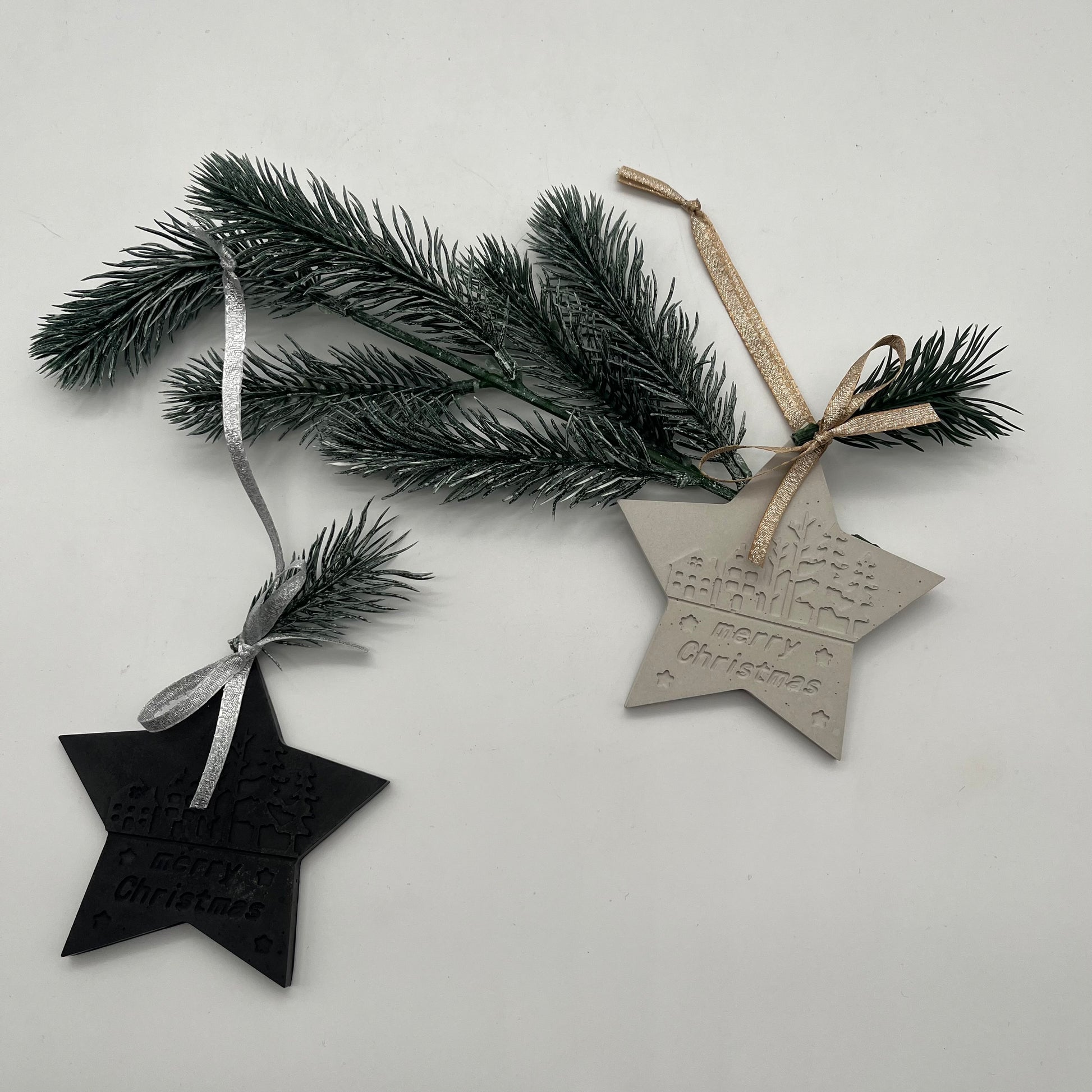 Beton-Anhänger Stern „Christmas Magic“ in Grau und Schwarz auf Tannenzweig – moderne Weihnachtsdeko.