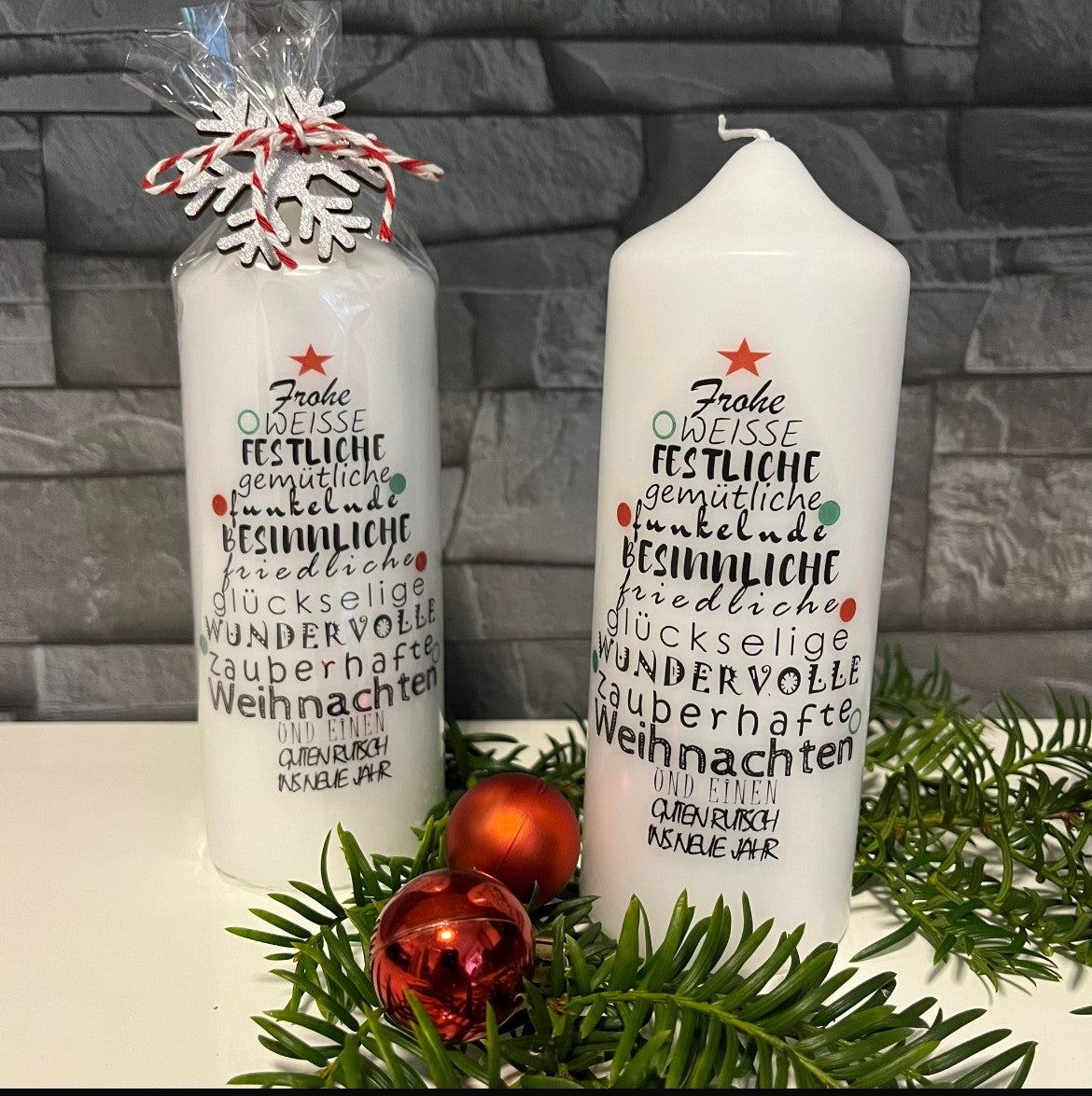 Handgefertigte Weihnachtskerzen rund, verpackt und unverpackt, festlich arrangiert mit Tannengrün und Christbaumkugel